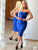 A woman wearing a blue strapless ruched dress with a fitted silhouette, standing in front of a mirror.