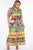 A woman wearing a colorful maxi dress with a caretto print, featuring a floral design and a tie around the waist.